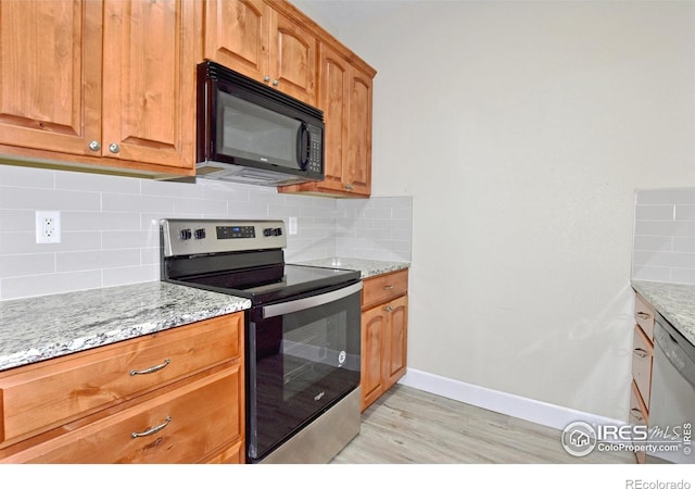 kitchen featuring decorative backsplash, light stone countertops, light hardwood / wood-style floors, and appliances with stainless steel finishes