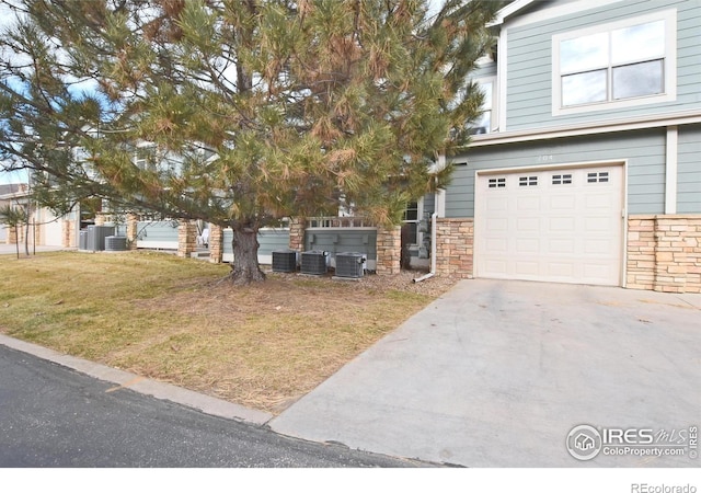 view of front of property featuring central AC unit, a front yard, and a garage