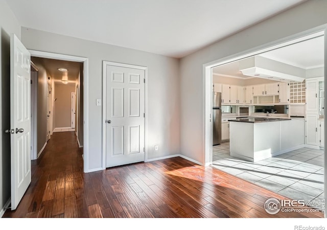 kitchen with kitchen peninsula, light wood-type flooring, white cabinetry, and stainless steel refrigerator