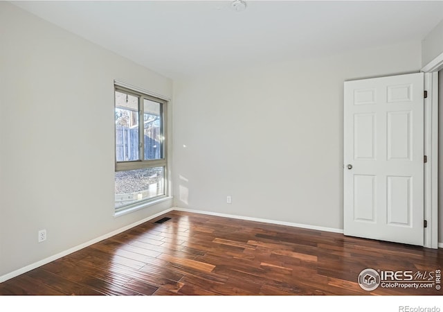 spare room with dark wood-type flooring