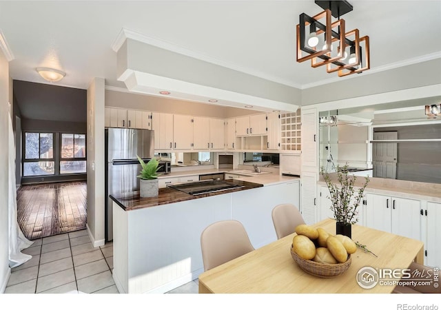 kitchen with stainless steel fridge, crown molding, light tile patterned floors, and hanging light fixtures