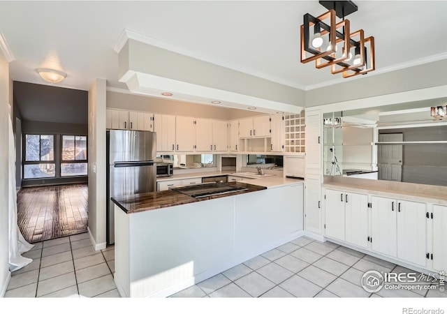 kitchen featuring white cabinets, light tile patterned floors, appliances with stainless steel finishes, and ornamental molding