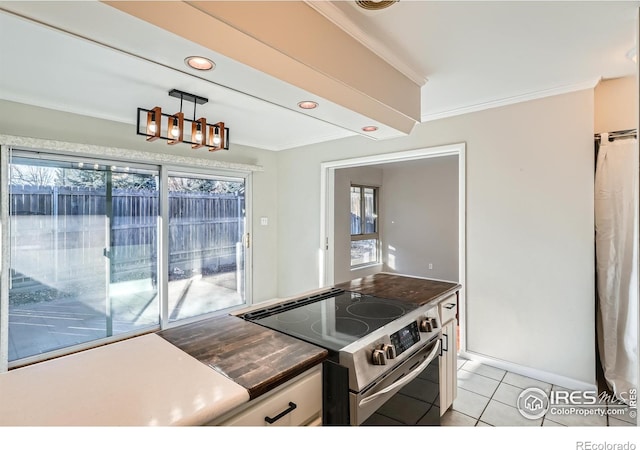 kitchen featuring stainless steel range with electric cooktop, crown molding, hanging light fixtures, light tile patterned floors, and white cabinetry