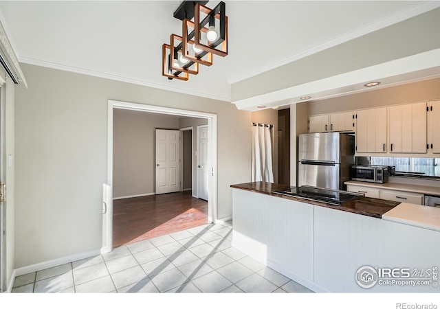 kitchen featuring decorative light fixtures, light tile patterned floors, stainless steel appliances, and ornamental molding