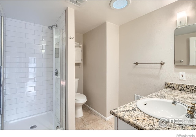 bathroom featuring tile patterned flooring, a tile shower, vanity, and toilet