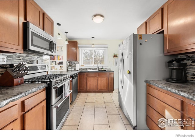 kitchen with decorative backsplash, pendant lighting, stainless steel appliances, and sink