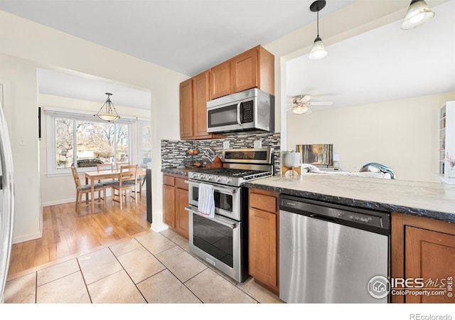 kitchen with pendant lighting, ceiling fan, light tile patterned floors, tasteful backsplash, and stainless steel appliances