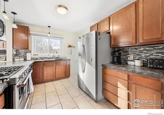 kitchen featuring decorative backsplash, pendant lighting, appliances with stainless steel finishes, and sink