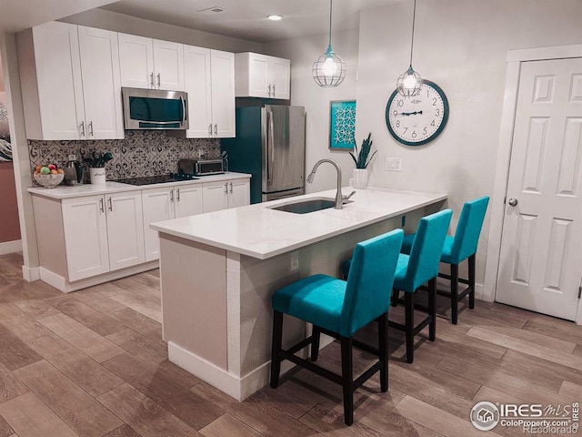 kitchen with white cabinets, appliances with stainless steel finishes, a kitchen breakfast bar, and pendant lighting