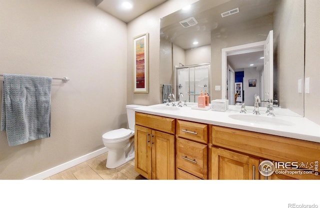 bathroom with toilet, vanity, tile patterned floors, and a shower with door