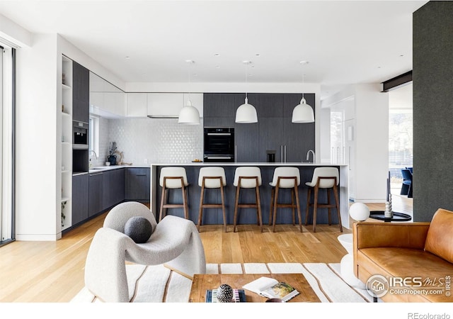 kitchen with a breakfast bar, hanging light fixtures, and light hardwood / wood-style flooring