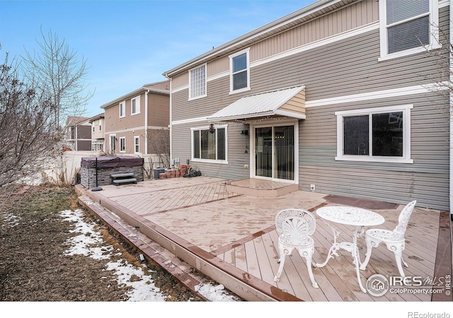 snow covered rear of property featuring a hot tub and a wooden deck