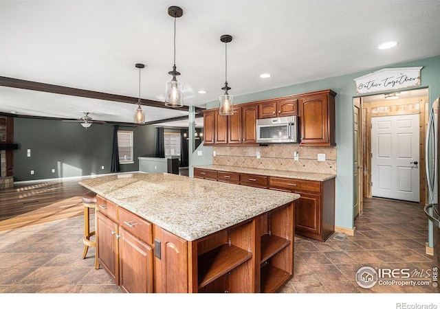 kitchen with a kitchen bar, backsplash, ceiling fan, pendant lighting, and a center island