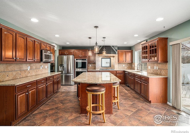 kitchen with sink, appliances with stainless steel finishes, tasteful backsplash, decorative light fixtures, and a kitchen island