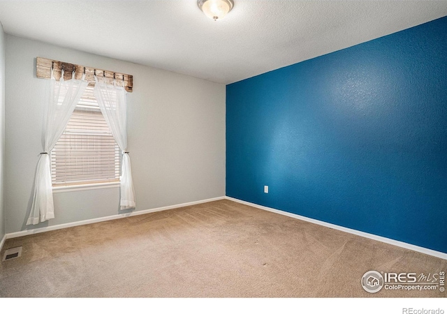 carpeted spare room featuring a textured ceiling