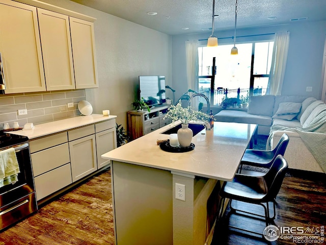 kitchen with a center island with sink, a kitchen breakfast bar, white cabinets, electric range, and tasteful backsplash