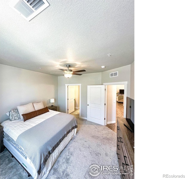 carpeted bedroom with ceiling fan and a textured ceiling