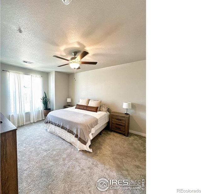 bedroom with ceiling fan, light colored carpet, and a textured ceiling