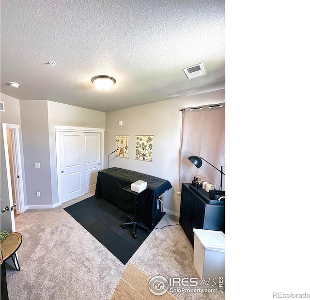 carpeted office space featuring a textured ceiling