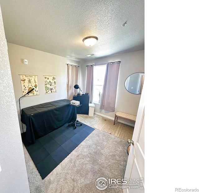 bedroom with a textured ceiling and light carpet