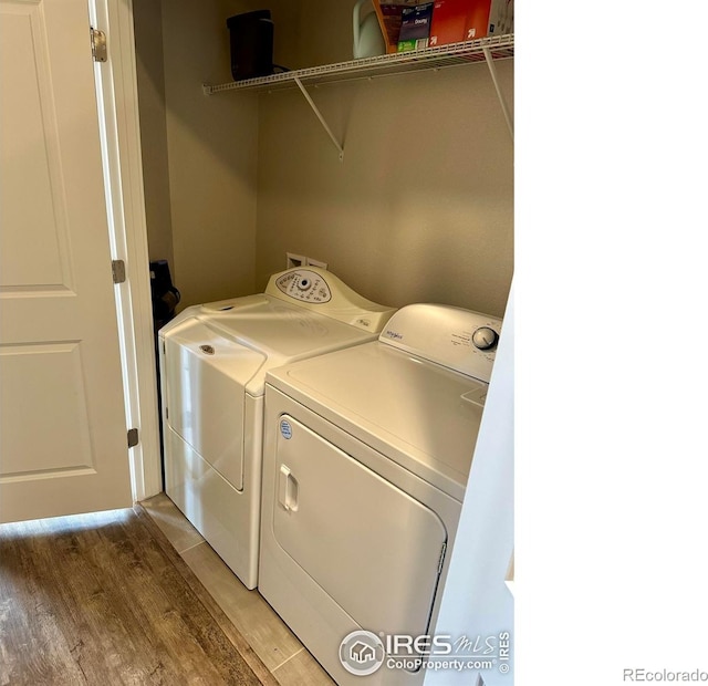 clothes washing area with washing machine and dryer and hardwood / wood-style flooring