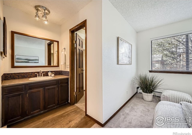 interior space featuring hardwood / wood-style floors, vanity, a textured ceiling, and a baseboard heating unit