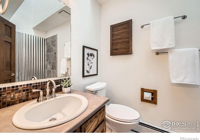 bathroom with backsplash, toilet, vanity, and a baseboard heating unit