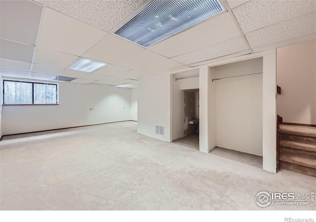 basement with a paneled ceiling and carpet