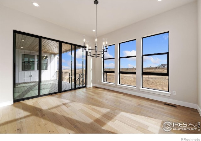 unfurnished dining area with hardwood / wood-style flooring and a notable chandelier