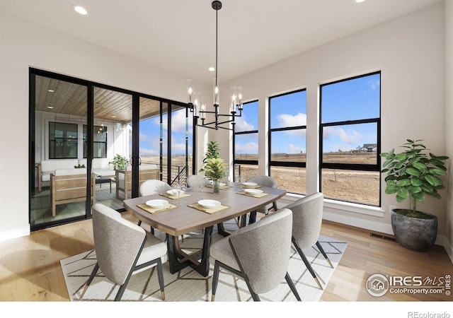 dining area with an inviting chandelier and light hardwood / wood-style floors