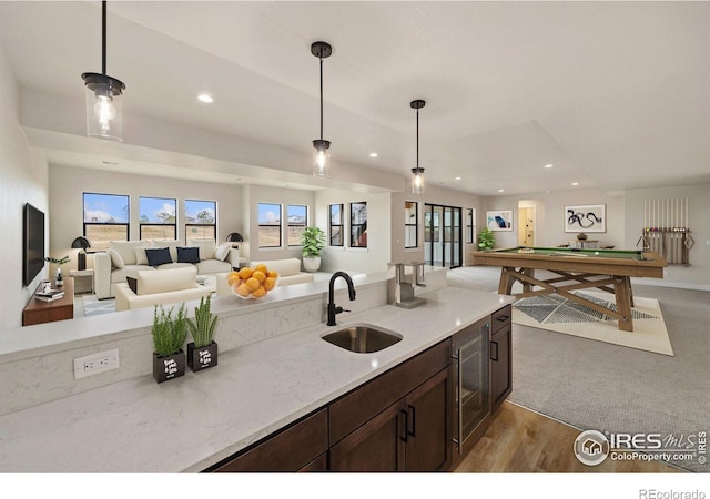 kitchen featuring light stone countertops, sink, pendant lighting, and billiards