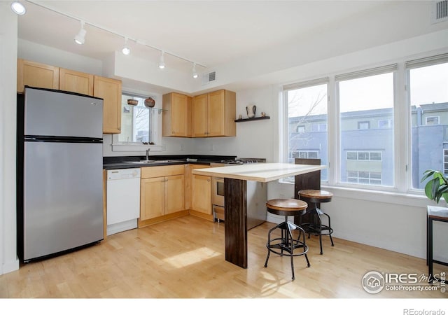 kitchen featuring light hardwood / wood-style floors, light brown cabinetry, sink, and appliances with stainless steel finishes