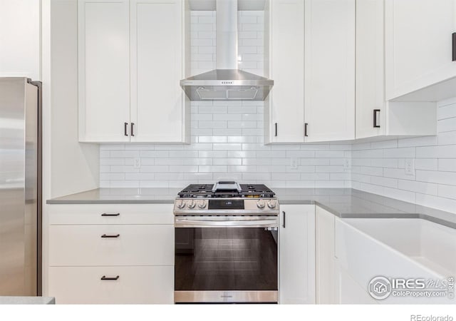 kitchen featuring white cabinets, wall chimney exhaust hood, stainless steel appliances, and tasteful backsplash