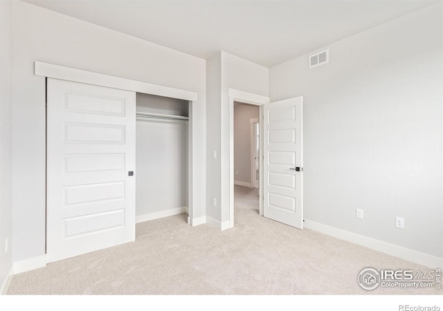 unfurnished bedroom featuring a closet and light colored carpet