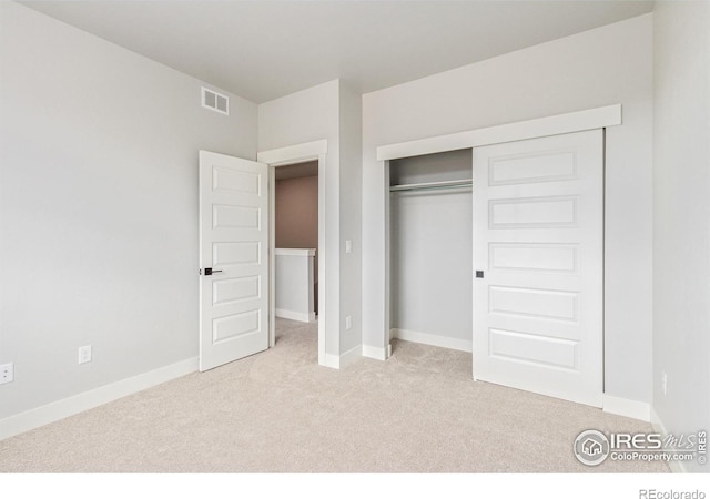 unfurnished bedroom featuring a closet and light colored carpet