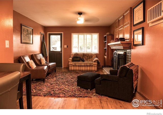 living room with ceiling fan, light hardwood / wood-style flooring, and a brick fireplace