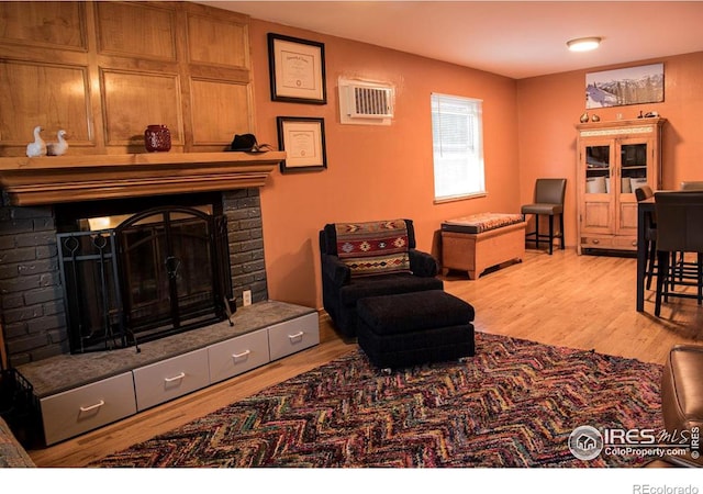 living room with a wall unit AC, a fireplace, and wood finished floors