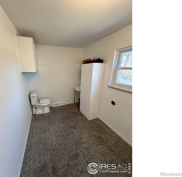 bathroom with baseboards, visible vents, vanity, and toilet