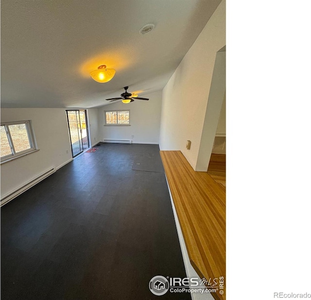 unfurnished living room with lofted ceiling, a baseboard heating unit, and a ceiling fan