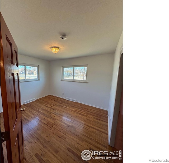 unfurnished bedroom featuring baseboards, visible vents, and dark wood finished floors