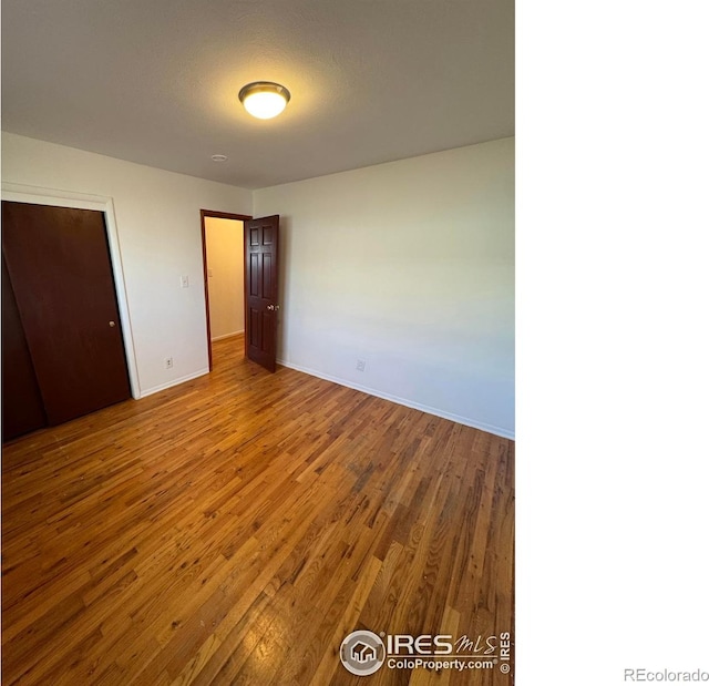 unfurnished bedroom with wood finished floors and baseboards