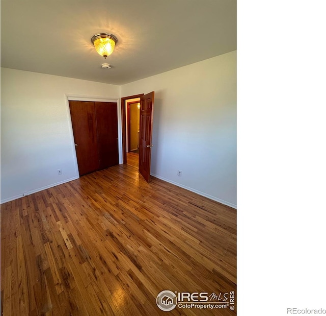 unfurnished bedroom featuring a closet, baseboards, and wood finished floors