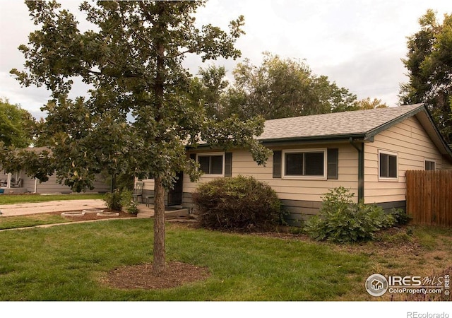 view of front facade with roof with shingles, a front yard, and fence