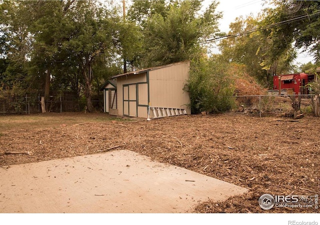 view of yard with an outdoor structure, a patio, a storage shed, and fence