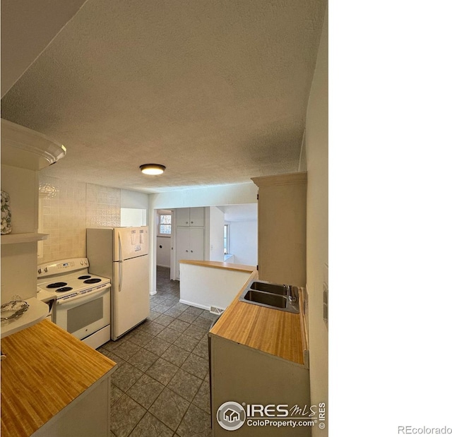 6213 Gray St, Arvada, CO 80003 - kitchen with white appliances, a sink, a textured ceiling, and dark tile patterned floors