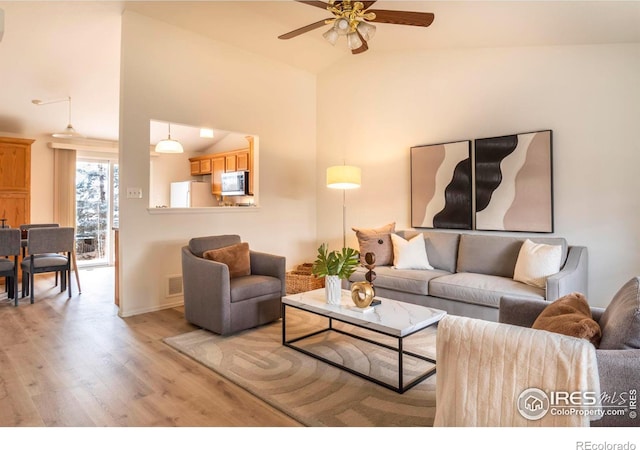 living room featuring light wood-type flooring, vaulted ceiling, and ceiling fan