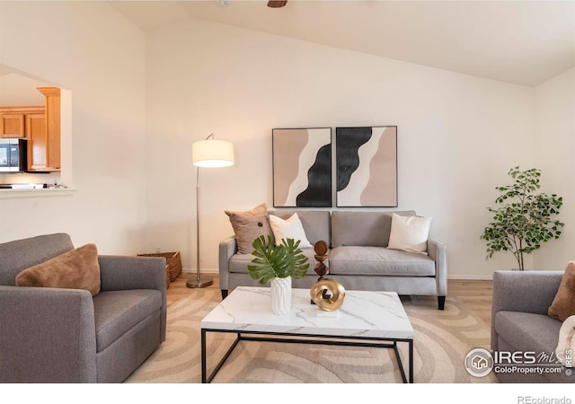 living room featuring light wood-type flooring and vaulted ceiling