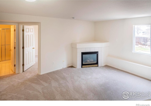 unfurnished living room with a tile fireplace and light colored carpet