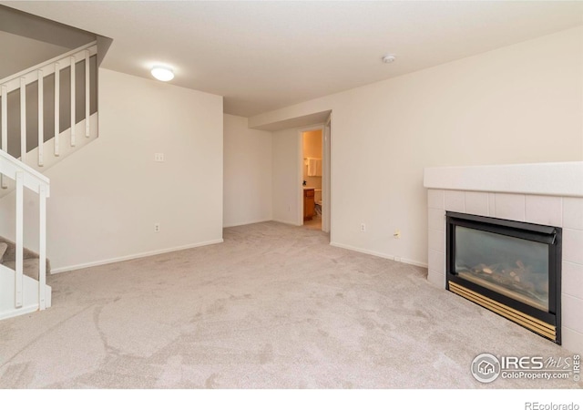 unfurnished living room featuring light colored carpet and a tiled fireplace