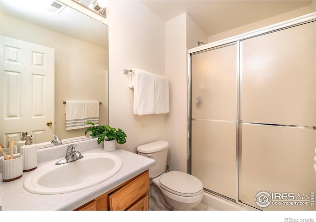 bathroom with vanity, a shower with shower door, and toilet